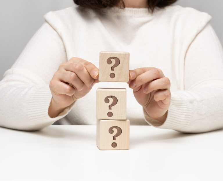female hand holding a wooden cube with a question mark, concept of answers and questions